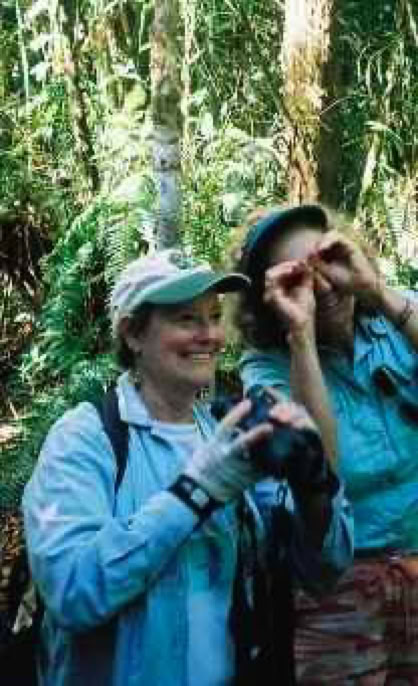 Two women in outdoor clothing and hats, one holding binoculars, the other pretending to